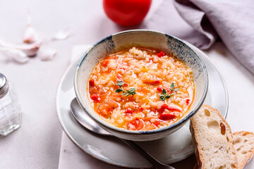 Vegetarian spicy tomato rice soup on grey concrete background. Selective focus