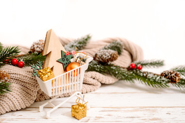 Christmas gift boxes in a shopping cart with decorative snowflackes around, Christmas sale concept. cozy knitted sweater.