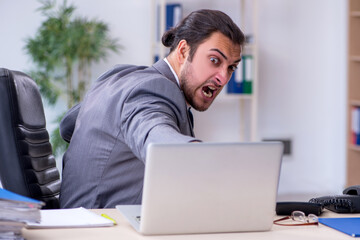 Young male employee unhappy with excessive work in the office