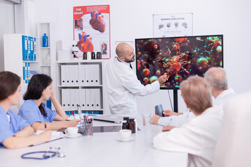 Doctor holding presentation about coroanvirus symptoms in front omf medical team. Specialist doctor discussing with colleagues about global pandemic because of dangerous virus,