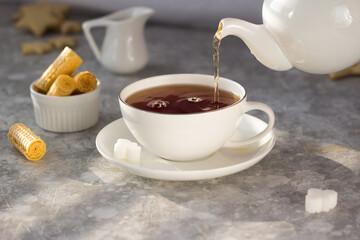 Tea from the teapot is poured into a white mug. A stream of tea pours into the Cup with a splash