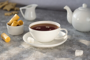 Tea from the teapot is poured into a white mug. A stream of tea pours into the Cup with a splash