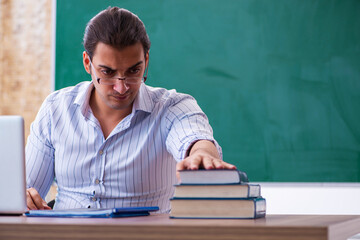 Young male teacher in front of blackboard