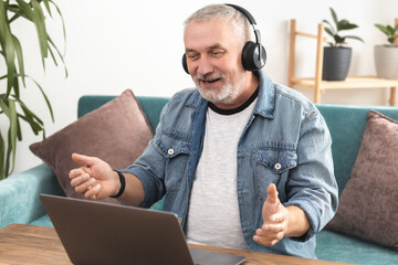 Adult man in wireless headphones communicates online