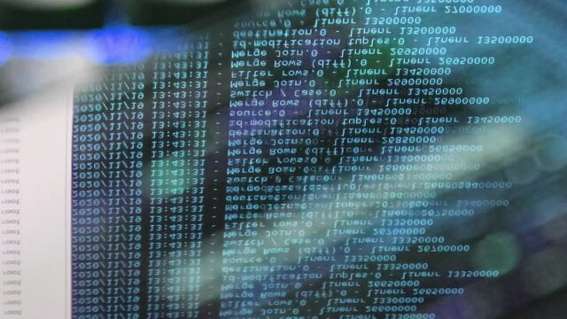 blue computer software code moving on a black monitor reflect on glass. Abstract computer hacking in process with rack server base, dynamic text running and flowing on pc screen