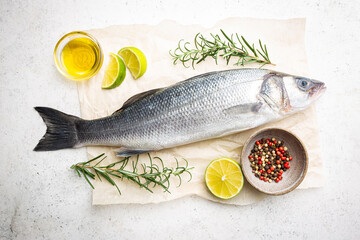 Raw seabass fish with rosemary and spices on white background, top view