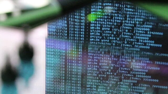 blue computer software code moving on a black monitor reflect on glass. Abstract computer hacking in process with rack server base, dynamic text running and flowing on pc screen