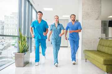Three doctors running throtugh the hospital corridor being in a hurry