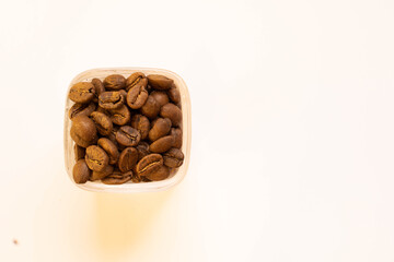 Brown, roasted coffee beans in a cup on the left