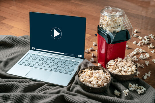 View of a laptop and a popcorn machine. Concept of watching movies or series at home