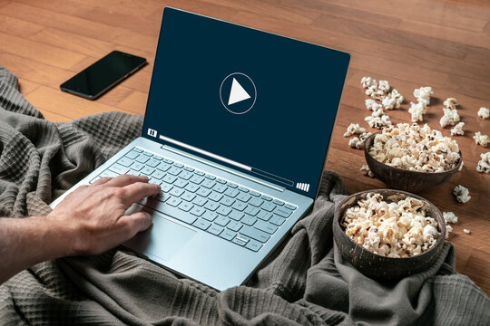 A person watching a movie or series in a laptop at home with popcorn. Concept of watching series or cinema by streaming