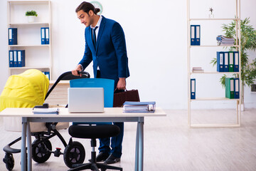 Young male employee looking after kid at workplace
