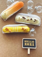 Christmas 2021 eclairs with new year balls on craft brown background.