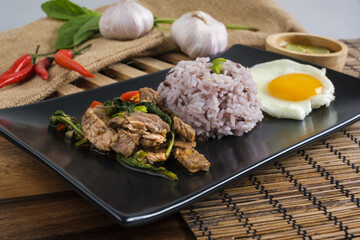 Stir-fried beef basil with fried egg and riceberry rice.