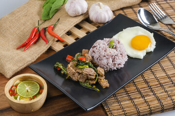 Stir-fried beef basil with fried egg and riceberry rice.