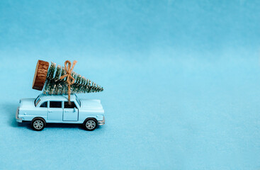 A toy car is driving a Christmas tree. On a blue background