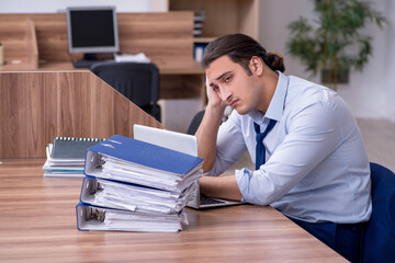Fototapeta premium Young male employee unhappy with excessive work