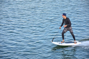 Motosurf Competitor taking corner at speed making a lot of spray. Jet surfing on a water, man riding on jet surfboard. Surfer in motion, summer sport