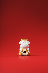 Cow figurine on a red background, new year's concept. Free space.