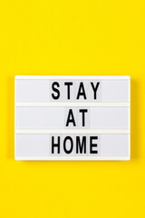 Lightbox with text STAY AT HOME on yellow background. Healthcare, medical, quarantine concept