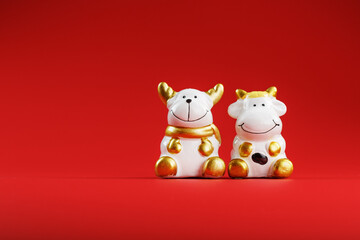 A pair of cow and bull Figures on a red background, with free space.