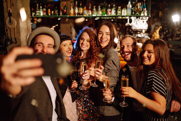 Group of friends having fun taking selfie with the phone while enjoying party in the club. Group of...