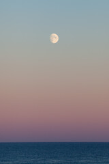 The moon over the ocean horizon in the Baltic Sea. Sunset during summertime.