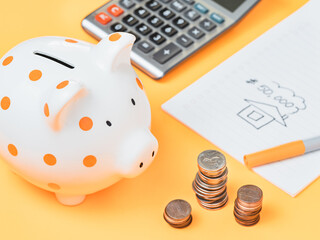 Piggy bank with stuck of coins and a notepad.