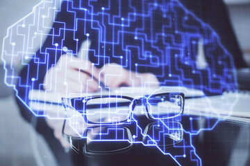 Double exposure of writing hand on background with brain hologram. Concept of learning.