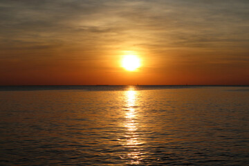 Obraz premium landscape photo of sunset reflect over the sea with clouds in the sky at the beach with shadow of rocks in the summer at Pattaya beach Thailand
