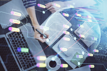 Double exposure of hands making notes with world map hologram and data theme icons. Concept of international network data.