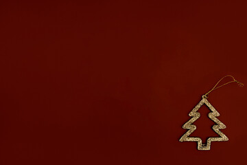 Obraz premium Minimalistic golden Christmas tree on a brown background. New year simple composition. Merry Christmas and happy New Year greeting card.