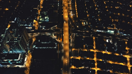 Aerial night city traffic road at business center. Amazing urban metropolis centre highway with cars drive in neon lights. Glow cityscape streets, roads, modern buildings at cinematic drone shot