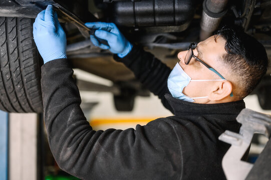 Auto Mechanic Man With Face Mask Working At Auto Repair Shop. High Quality Photo