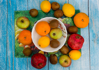 The fruit lies around a deep plate in which there are more fruit on a glass board, top view.