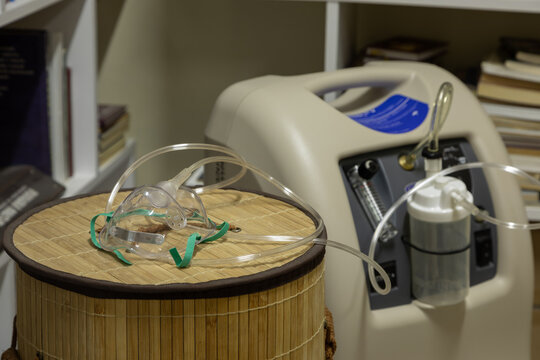 Stationary Medical Oxygen Concentrator With Attached Oxygen Mask On The Round Lid Of A Bamboo Basket In The Recreation Room Or Library. This Medical Equipment Is Useful For Respiratory Failure.