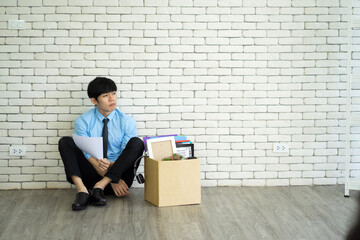 Asian business man misemployment feeling disappointed upset sitting on floor desperately in the office from financial problem 