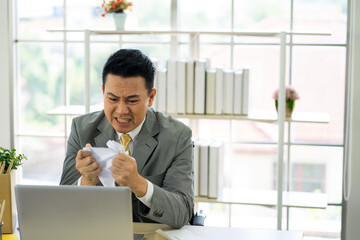 depressed worry Asian businessman wearing formal suit in the office feeling stressful from financial problem caused by virus pandemic. 