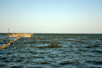 Fishing nets in the sea. The sun illuminates the fishing nets at sunset. Light excitement of the sea on a summer day.