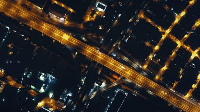 Top down night traffic highway with illuminated city streets aerial. Philippines downtown cityscape with modern architecture of skyscrapers buildings. Cinematic urban road at lantern lights drone shot
