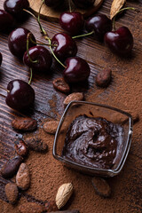 art background with healthy delicious dark truffles, chocolate  and  ingridients:  natural cocoa beans,  powder, chocolate, almonds  nuts and  ripe cherry. healthy sweets concept. close up