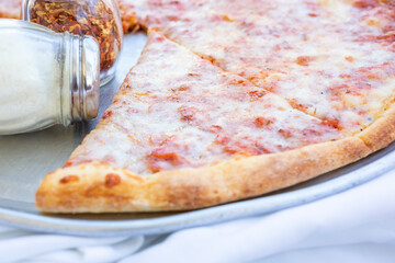 A view of a rustic cheese pizza, in a restaurant or kitchen setting.