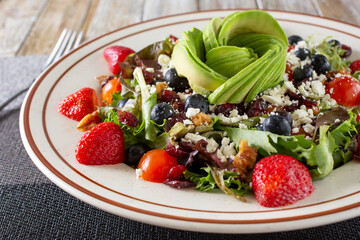 A view of a California salad, featuring avocado slices, berries, and feta cheese.