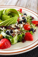 A view of a California salad, featuring avocado slices, berries, and feta cheese.