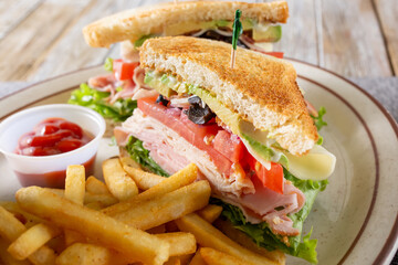 A view of a club sandwich plate, featuring a side of french fries.