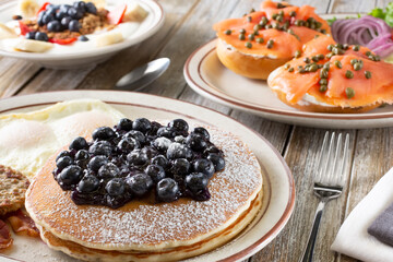 A closeup view of a pancake breakfast plate featured with several other breakfast and brunch plate on a table.