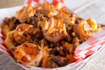 A view of a basket of loaded surf and turf french fries.