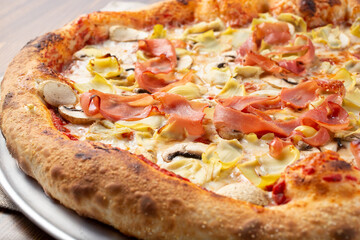 A closeup view of a rustic prosciutto and artichoke pizza pie.