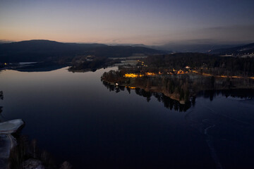 Drone or aerial photo from Oslo, Norway. Shot in late November in blue hours.  Winter is coming. Ground and trees are covered with snow frost, the lakes are freezing up.
