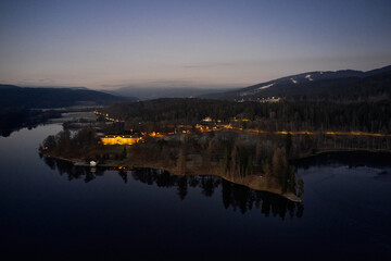 Drone or aerial photo from Oslo, Norway. Shot in late November in blue hours.  Winter is coming. Ground and trees are covered with snow frost, the lakes are freezing up.